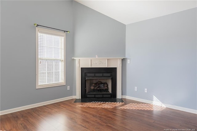 unfurnished living room with lofted ceiling, dark wood-type flooring, a fireplace with flush hearth, and baseboards