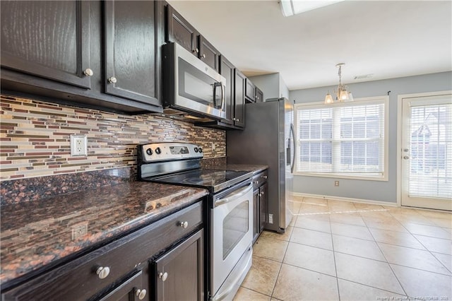 kitchen featuring dark stone counters, decorative backsplash, hanging light fixtures, stainless steel appliances, and light tile patterned flooring