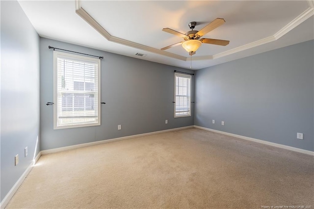 empty room with light carpet, ceiling fan, a tray ceiling, and baseboards