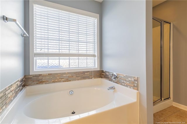 bathroom with a stall shower, tile patterned flooring, and a bath