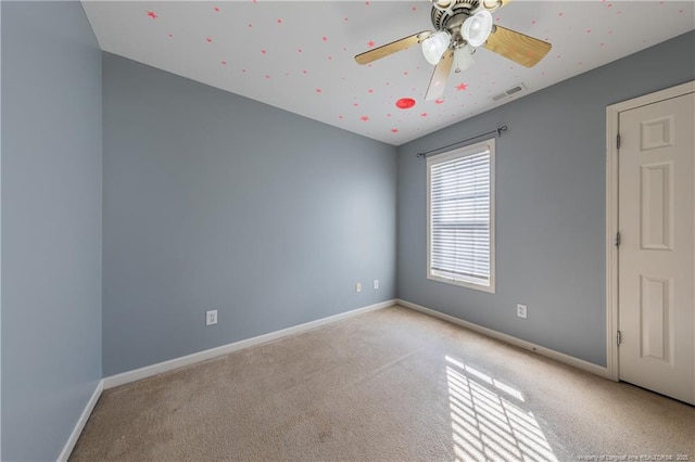 empty room featuring light carpet, ceiling fan, visible vents, and baseboards