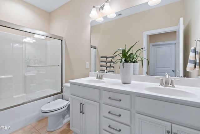 bathroom featuring toilet, tile patterned floors, double vanity, and a sink