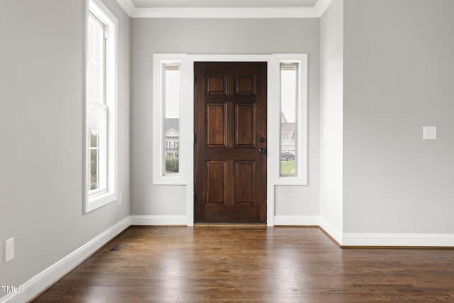 foyer with dark wood-type flooring, crown molding, and baseboards