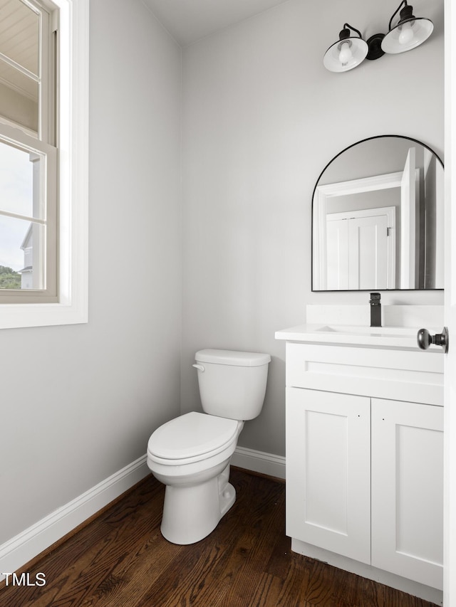 bathroom featuring toilet, vanity, baseboards, and wood finished floors