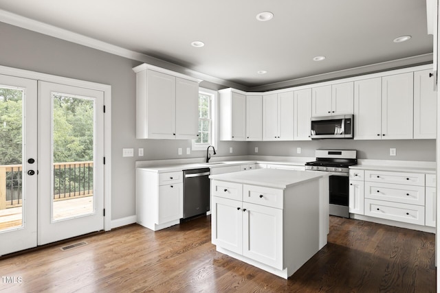 kitchen featuring light countertops, appliances with stainless steel finishes, a kitchen island, and white cabinetry