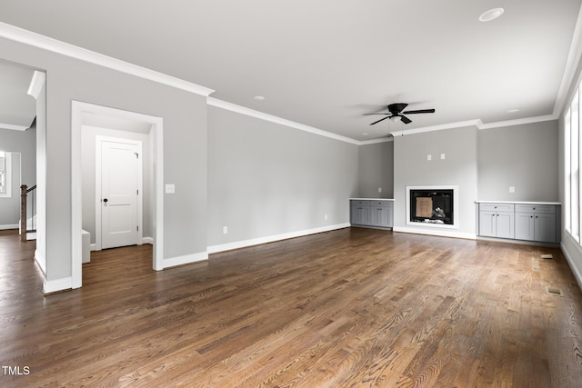 unfurnished living room featuring dark wood-style floors, a glass covered fireplace, a ceiling fan, and baseboards