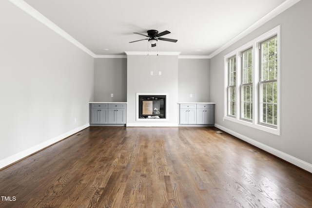 unfurnished living room featuring baseboards, ornamental molding, wood finished floors, and a glass covered fireplace