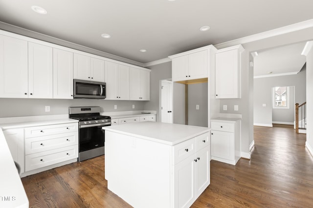 kitchen featuring white cabinets, ornamental molding, a center island, stainless steel appliances, and light countertops