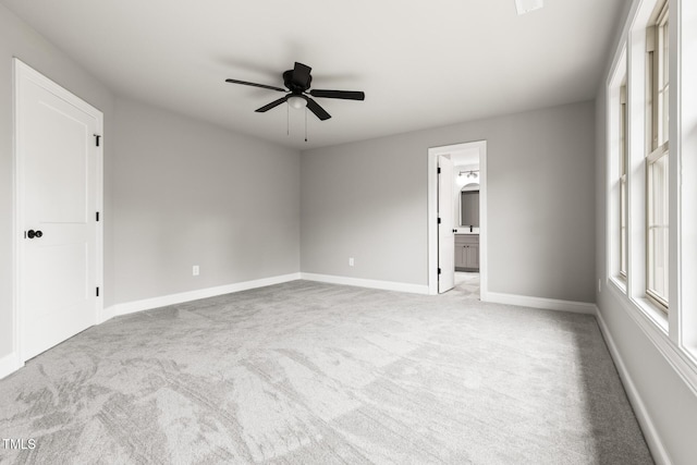 unfurnished room with a ceiling fan, light colored carpet, and baseboards