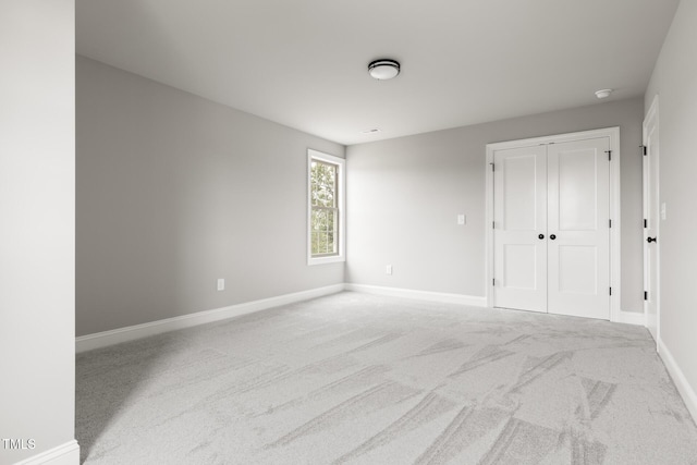 unfurnished bedroom with a closet, light carpet, and baseboards