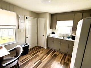 kitchen featuring dark wood-type flooring, freestanding refrigerator, light countertops, and a sink