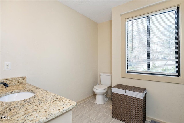 bathroom with tile patterned flooring, baseboards, vanity, and toilet