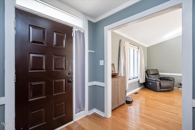 entrance foyer featuring a textured ceiling, light wood-type flooring, visible vents, and baseboards