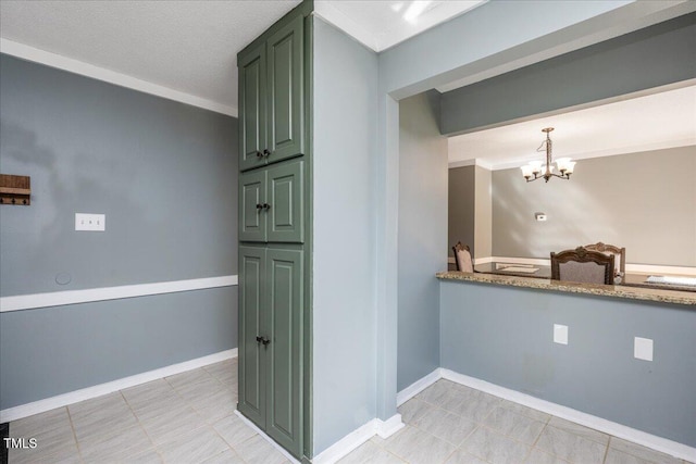 kitchen with green cabinets, a notable chandelier, and baseboards