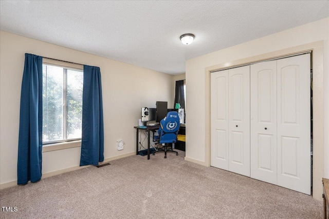 carpeted home office featuring visible vents, baseboards, and a textured ceiling