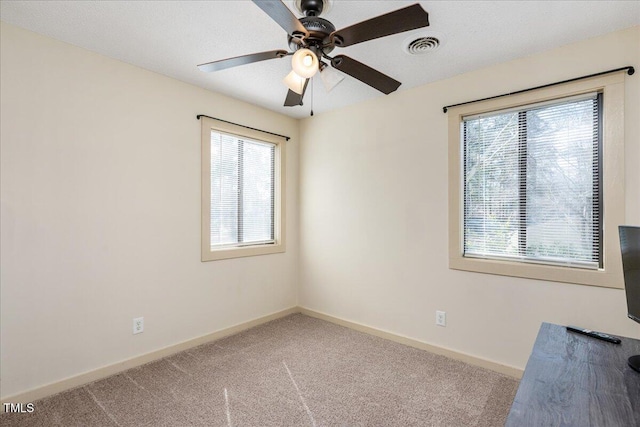 carpeted empty room with visible vents, ceiling fan, and baseboards