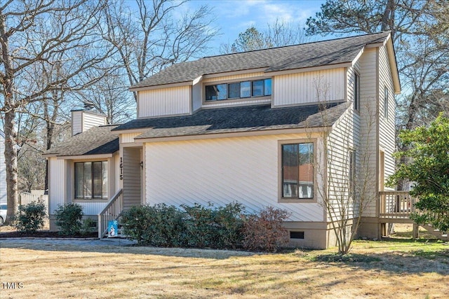 view of side of property with roof with shingles, crawl space, a chimney, and a lawn