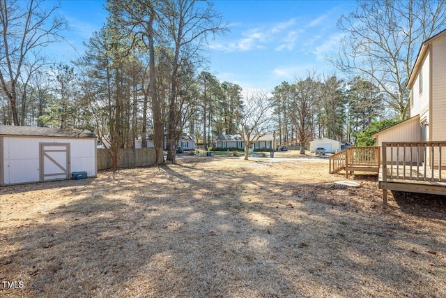 view of yard with an outbuilding, fence, a deck, and a storage unit