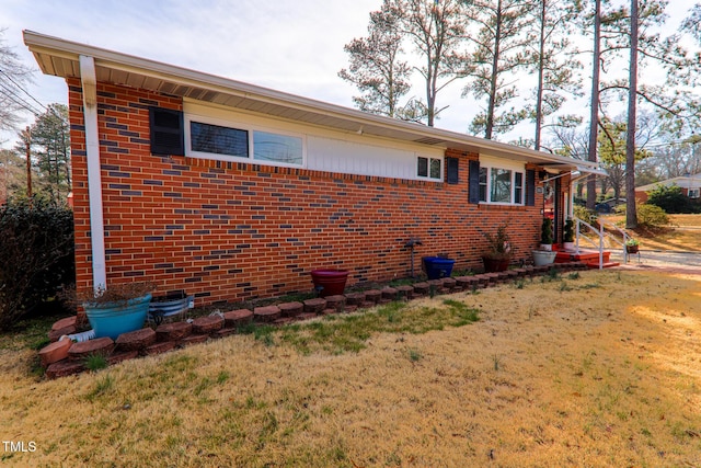 view of property exterior featuring brick siding and a lawn