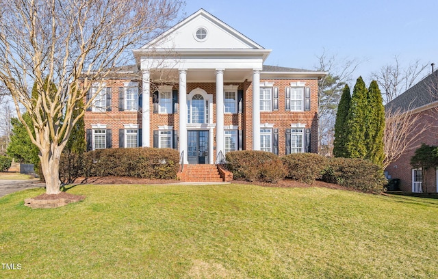 neoclassical home featuring brick siding and a front yard