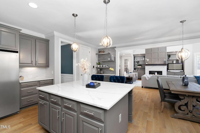 kitchen featuring a kitchen island, open floor plan, gray cabinets, stainless steel fridge, and pendant lighting