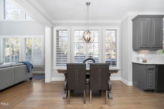 dining space with a chandelier, crown molding, baseboards, and wood finished floors