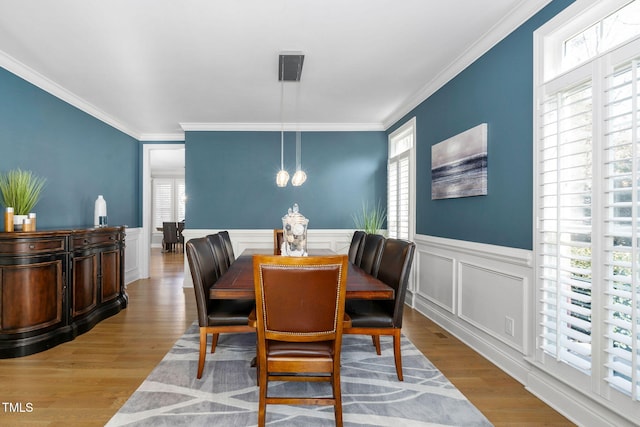 dining space featuring ornamental molding, light wood-style floors, and a healthy amount of sunlight