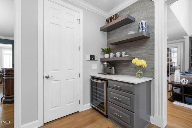 bar featuring a healthy amount of sunlight, light wood-style flooring, wine cooler, and crown molding