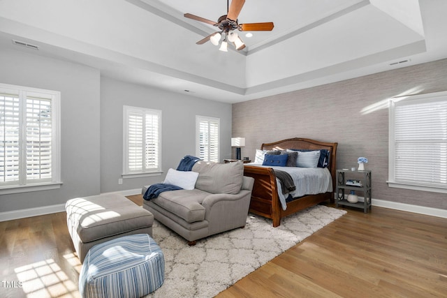 bedroom with multiple windows, wood finished floors, visible vents, and baseboards