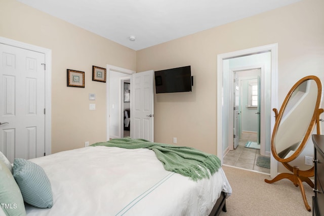 bedroom with light carpet, ensuite bath, and baseboards