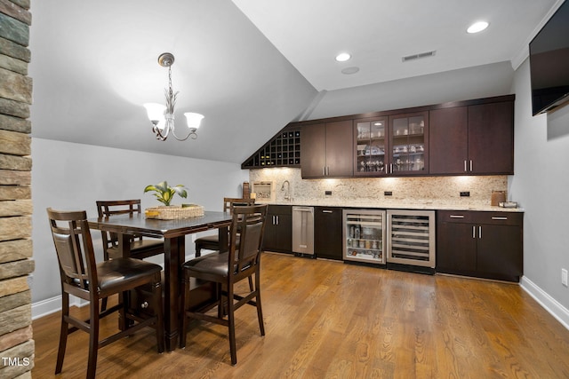 bar featuring wine cooler, decorative backsplash, indoor wet bar, and decorative light fixtures