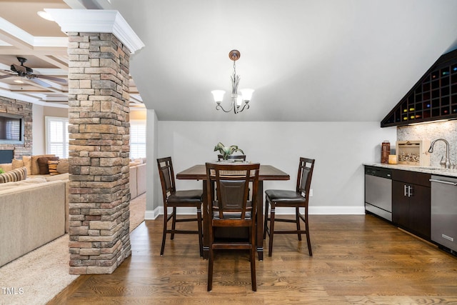 dining space with ceiling fan with notable chandelier, baseboards, dark wood finished floors, and ornate columns