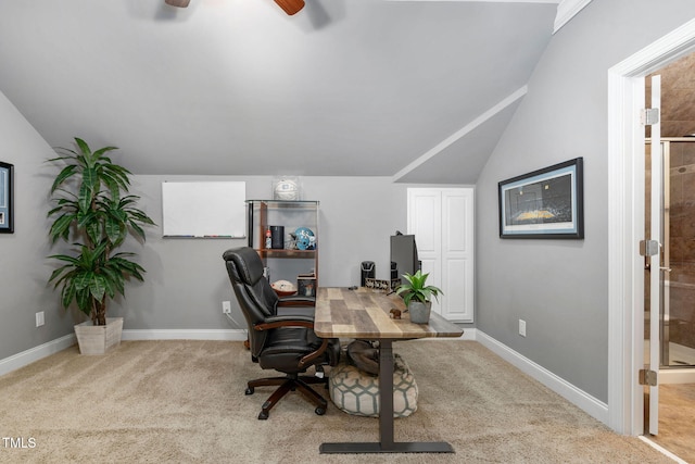 office space with a ceiling fan, light carpet, vaulted ceiling, and baseboards