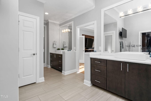 bathroom with two vanities, a sink, baseboards, a closet, and crown molding