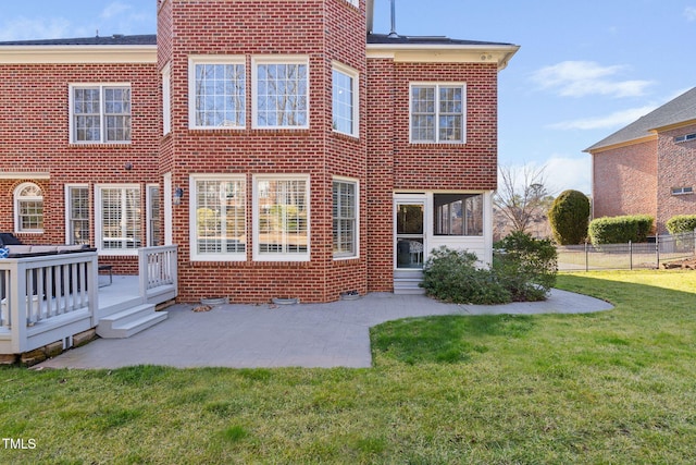 rear view of property featuring a patio area, a deck, a lawn, and brick siding