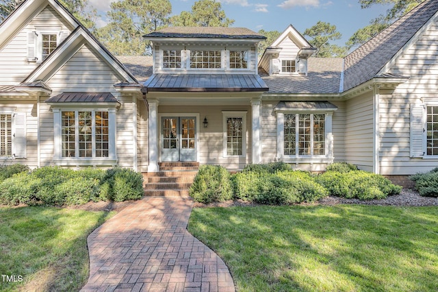 view of front facade with a standing seam roof, metal roof, and a front lawn