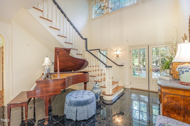foyer featuring stairs, granite finish floor, a towering ceiling, and baseboards