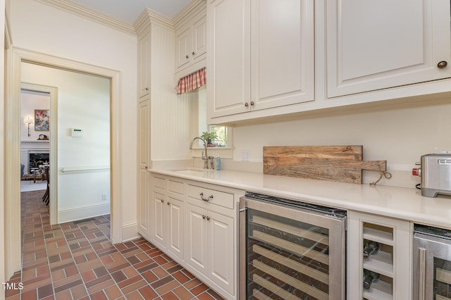 kitchen with brick floor, wine cooler, light countertops, and a sink