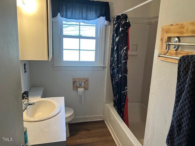 606 N Orange Ave, Dunn, NC 28334 - full bathroom with baseboards, toilet, shower / tub combo with curtain, wood finished floors, and vanity