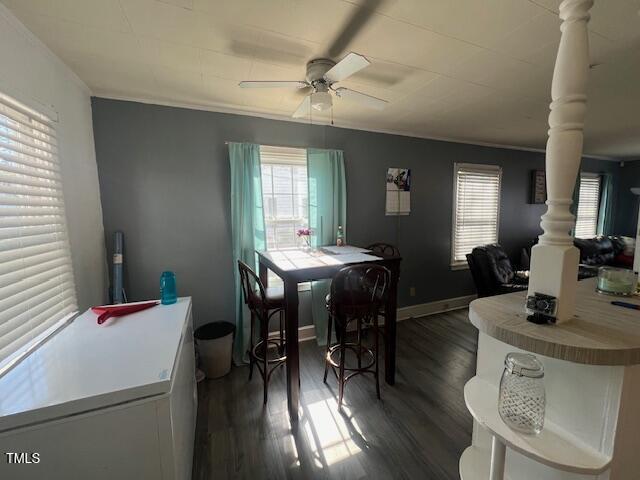 606 N Orange Ave, Dunn, NC 28334 - dining space with decorative columns, baseboards, ceiling fan, and dark wood-style flooring