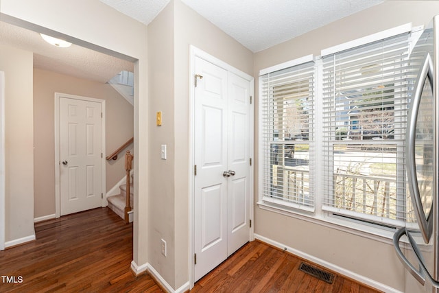 hall featuring a textured ceiling, stairway, wood finished floors, and visible vents