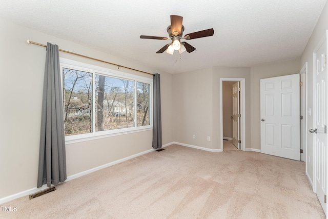 unfurnished bedroom featuring baseboards, light carpet, visible vents, and a textured ceiling