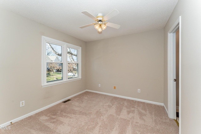 empty room with light colored carpet, visible vents, a textured ceiling, and baseboards