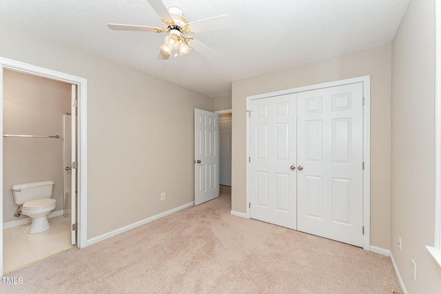 unfurnished bedroom featuring baseboards, connected bathroom, a textured ceiling, carpet flooring, and a closet