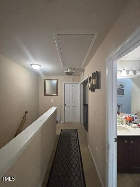 hall with attic access, a sink, and an upstairs landing