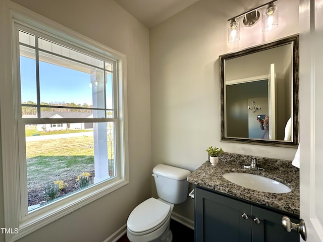 half bath featuring vanity, toilet, and baseboards