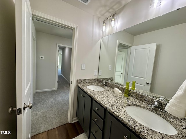 bathroom featuring double vanity, wood finished floors, baseboards, and a sink