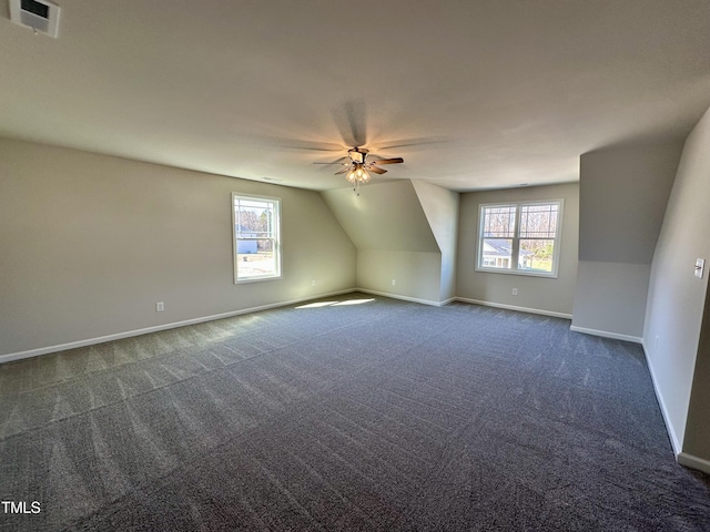 bonus room with visible vents, dark carpet, baseboards, and ceiling fan