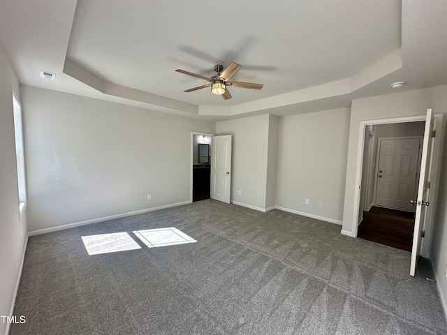 unfurnished bedroom with visible vents, a raised ceiling, a ceiling fan, carpet floors, and baseboards