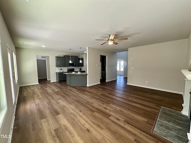 unfurnished living room with dark wood finished floors, a fireplace with flush hearth, baseboards, and ceiling fan